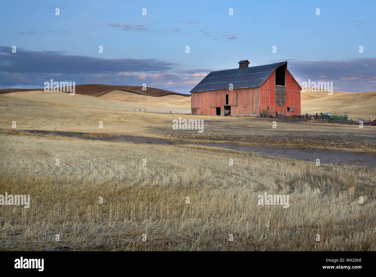 A red barn stands in the harvested wheat field in the Palouse region of eastern Washington. Stock Photo