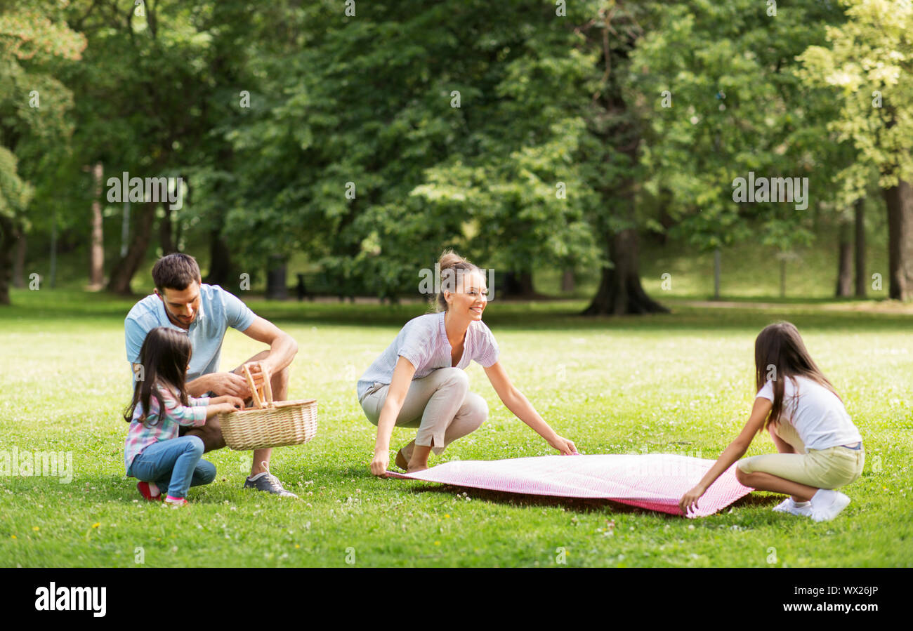 family laying down picnic blanket in summer park Stock Photo Alamy