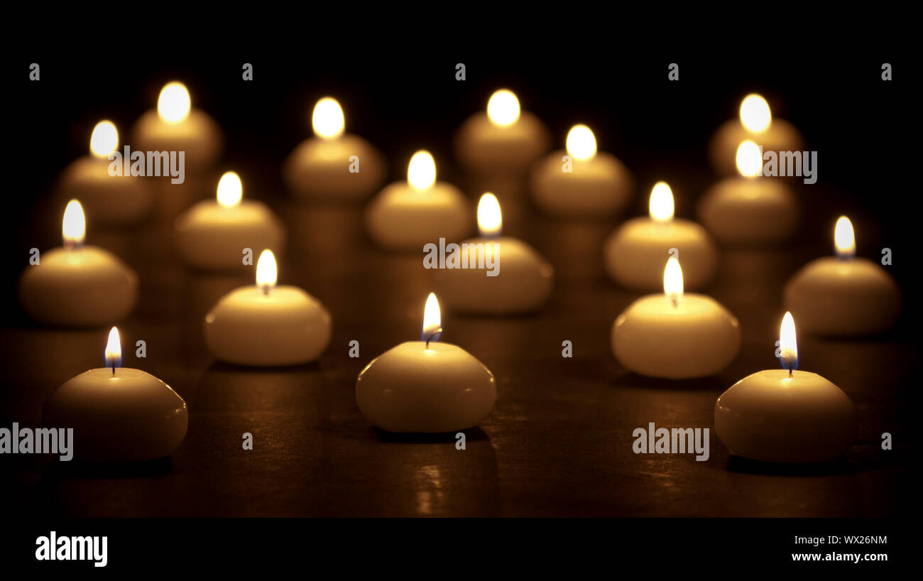 Group of burning candles at a black background with selective focus Stock Photo