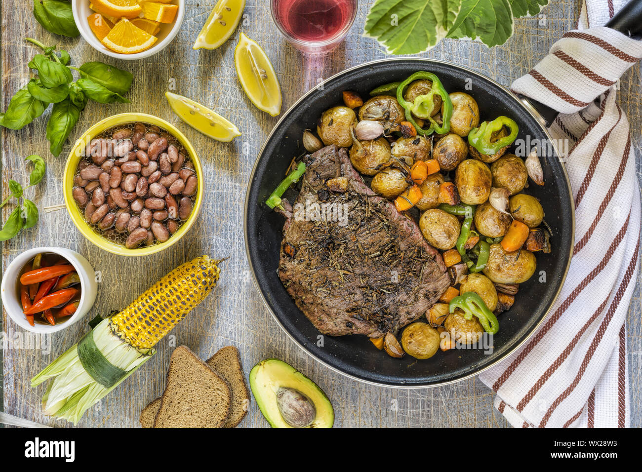 Juicy steak, table served, grilled vegetables, green basil, dining table Stock Photo