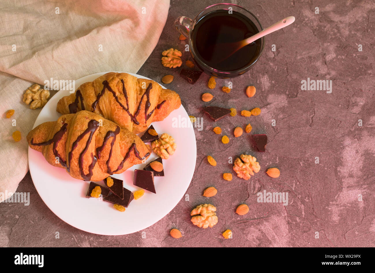 Two chocolate croissants raisins, nuts and a cup of coffee on a gray background. Top view. Breakfast concept. Stock Photo