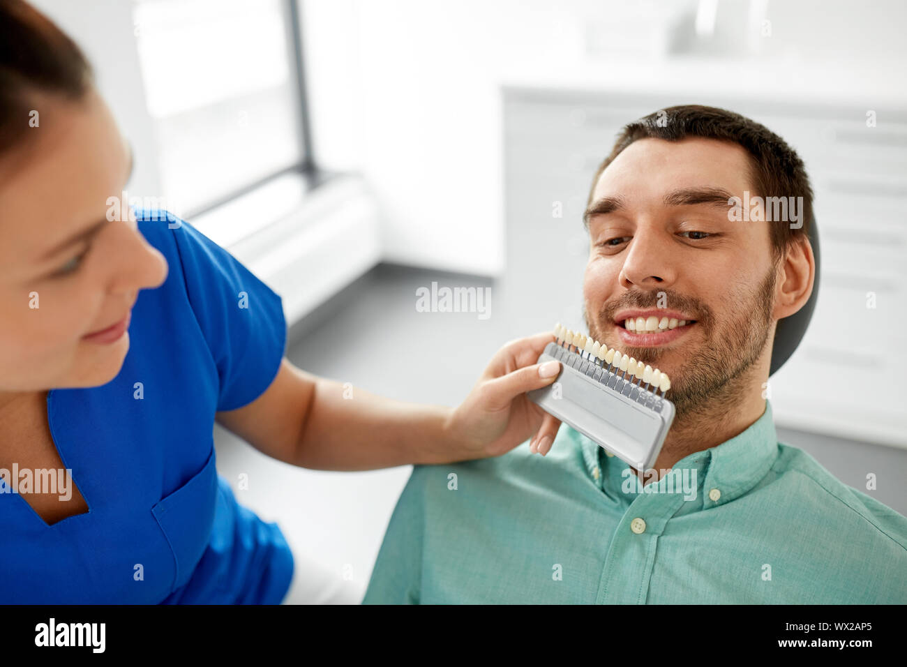 dentist choosing tooth color for patient at clinic Stock Photo