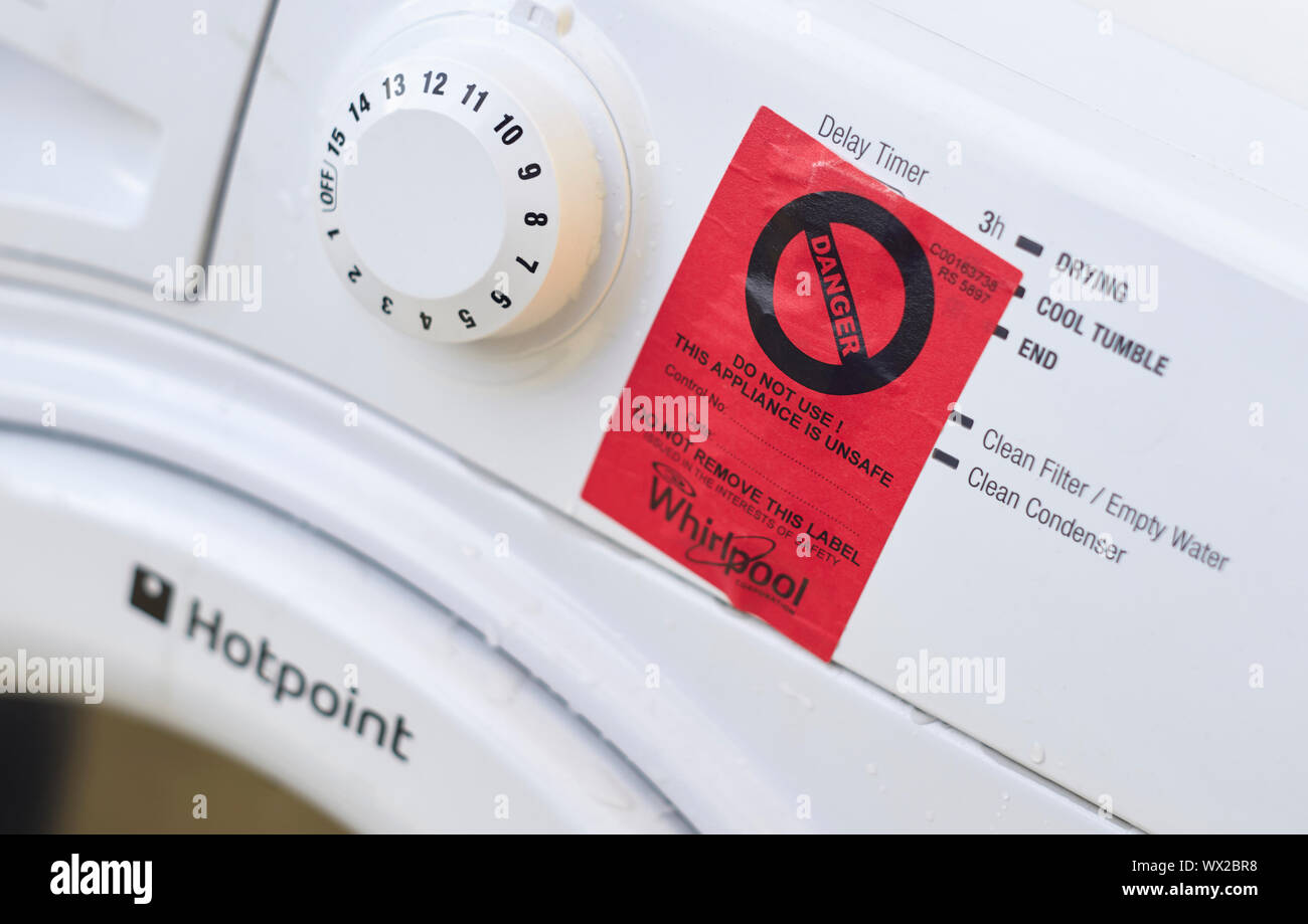 Red danger sign stuck on the front of a white Hotpoint Whirlpool tumble dryer Stock Photo