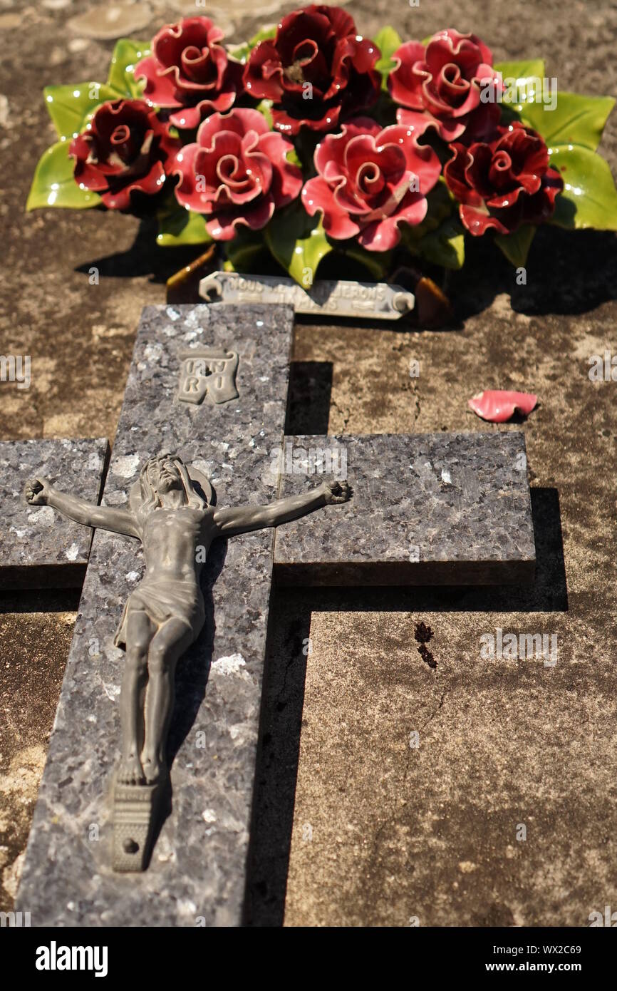 Jesus on the cross and flowers on a grave Stock Photo