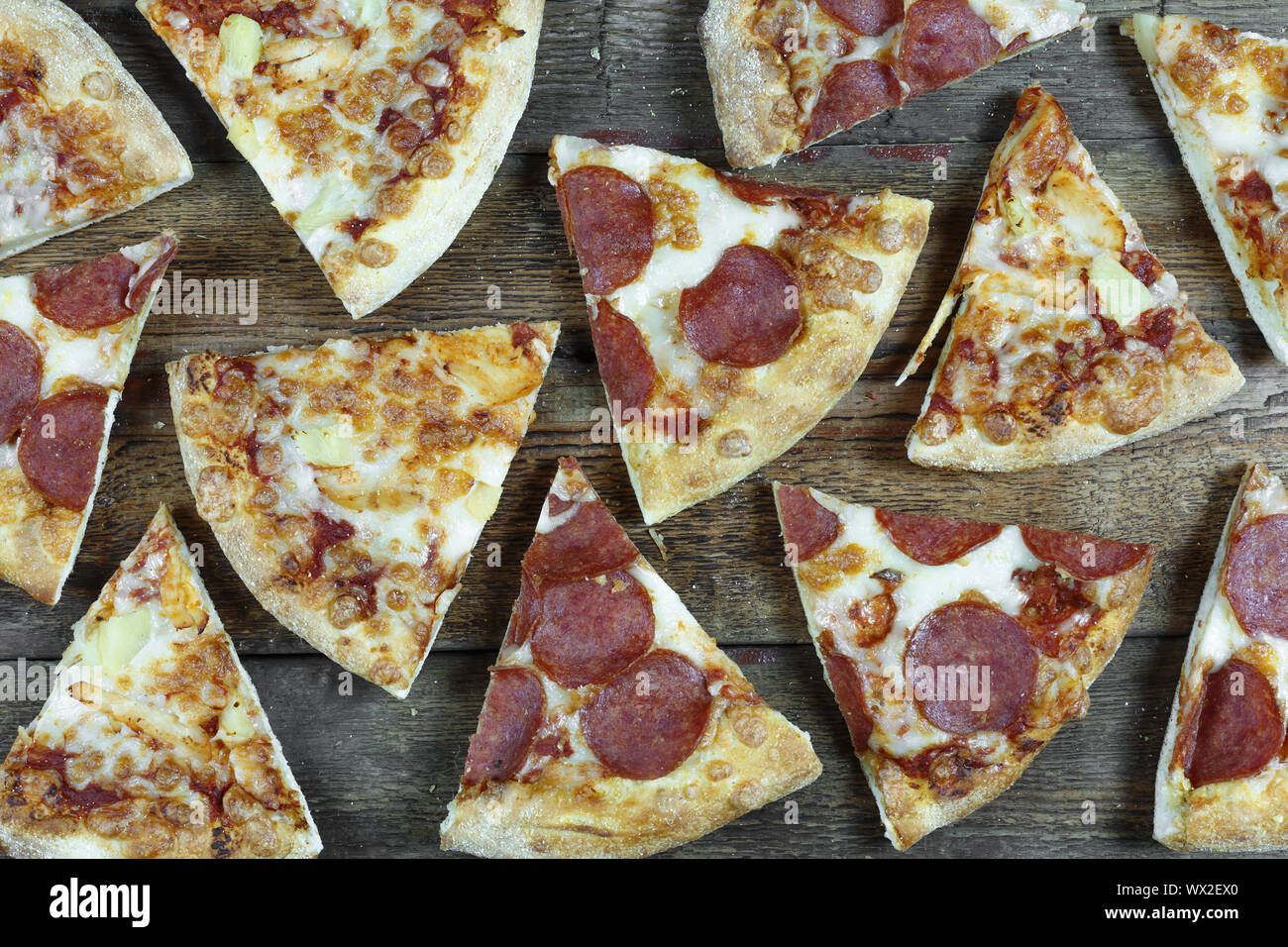 top view. Pizza-background. Pepperoni pizza and Hawaiian pizza cut into pieces on a wooden table. Cl Stock Photo