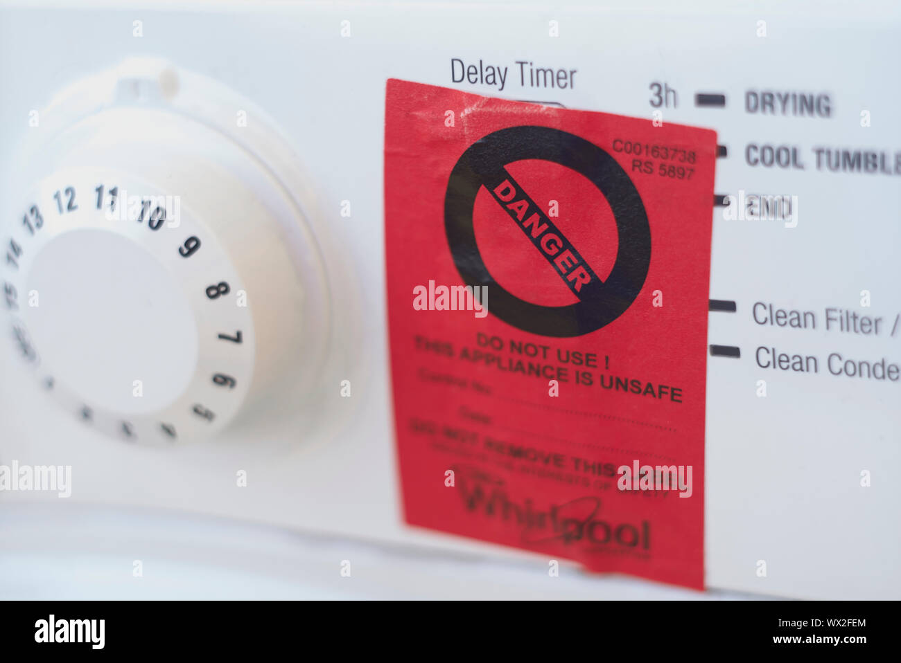 Red danger sign stuck on the front of a white Hotpoint Whirlpool tumble dryer Stock Photo