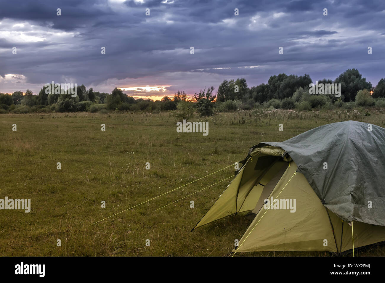 Tourist tent in the meadow in the evening. Stock Photo