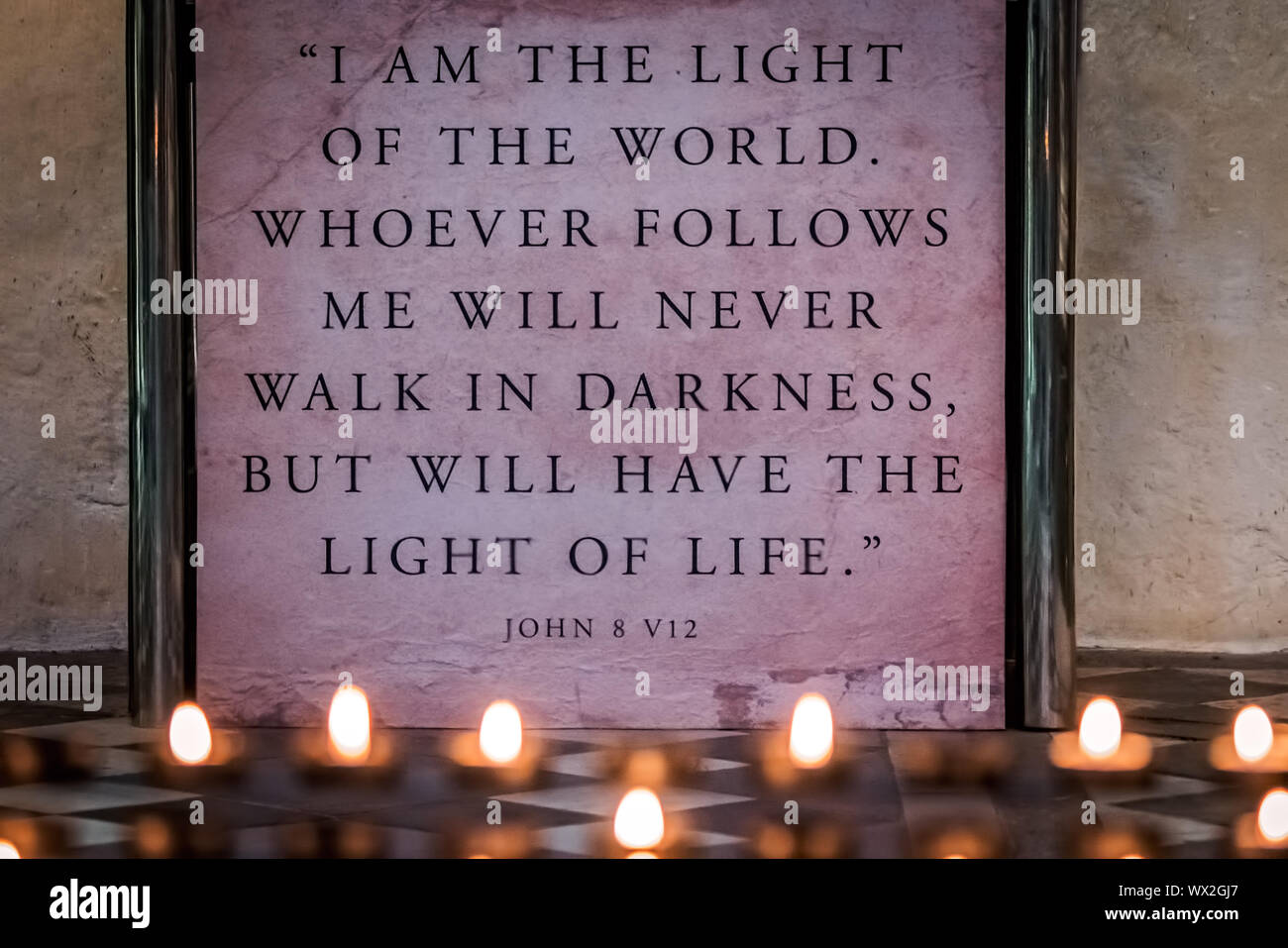 Memorial candles burning in front of a wall plaque with bible verse Stock Photo Alamy