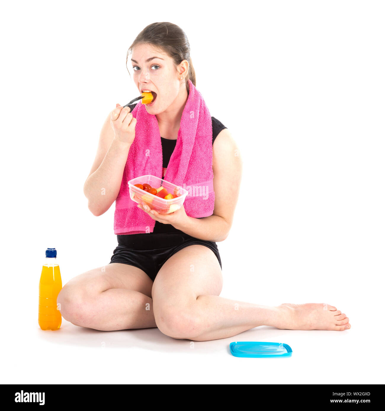 Front view of sitting woman with purple towel eating fresh fruits Stock Photo