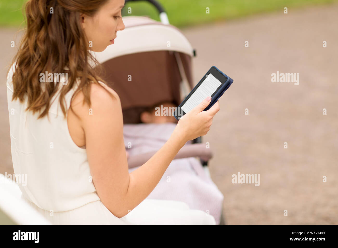 mother with stroller reading internet book at park Stock Photo