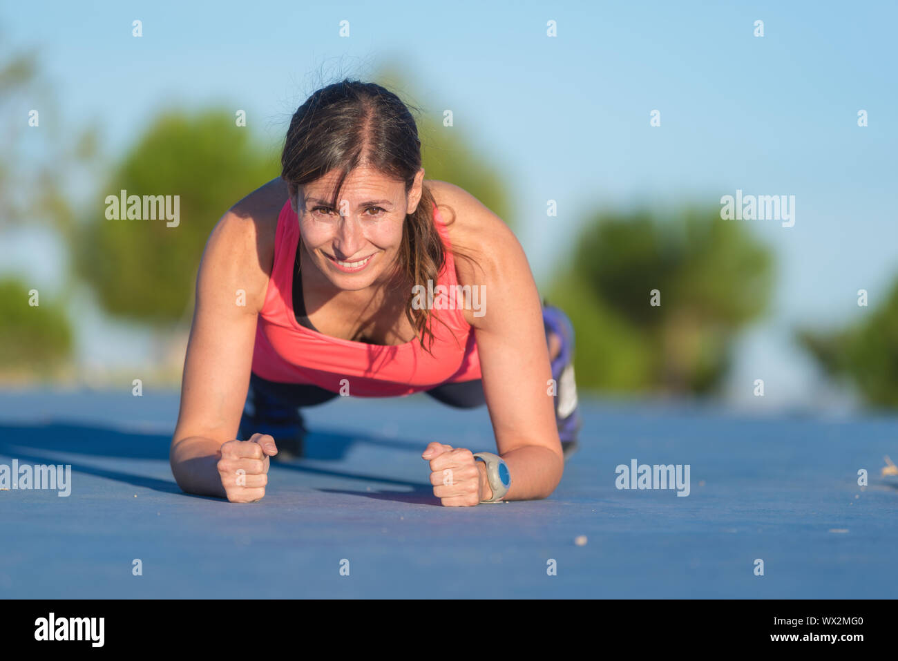 Fitness woman doing push-ups during outdoor cross training workout ...