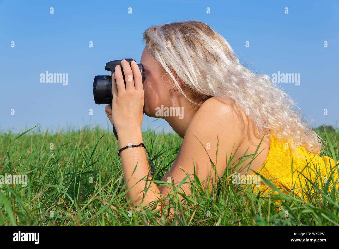 Young blond woman photographing in grass Stock Photo