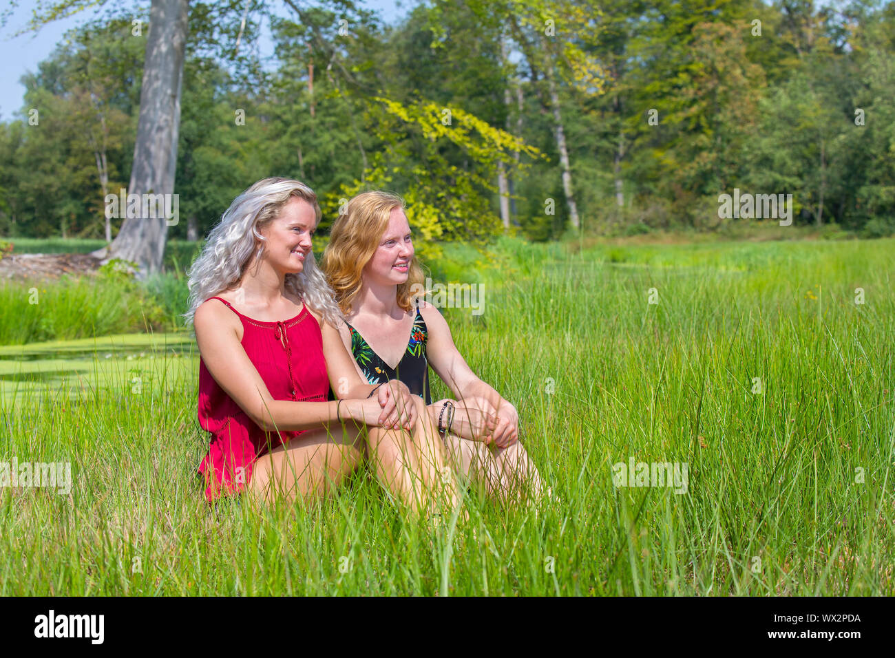Two young women sit together in nature Stock Photo