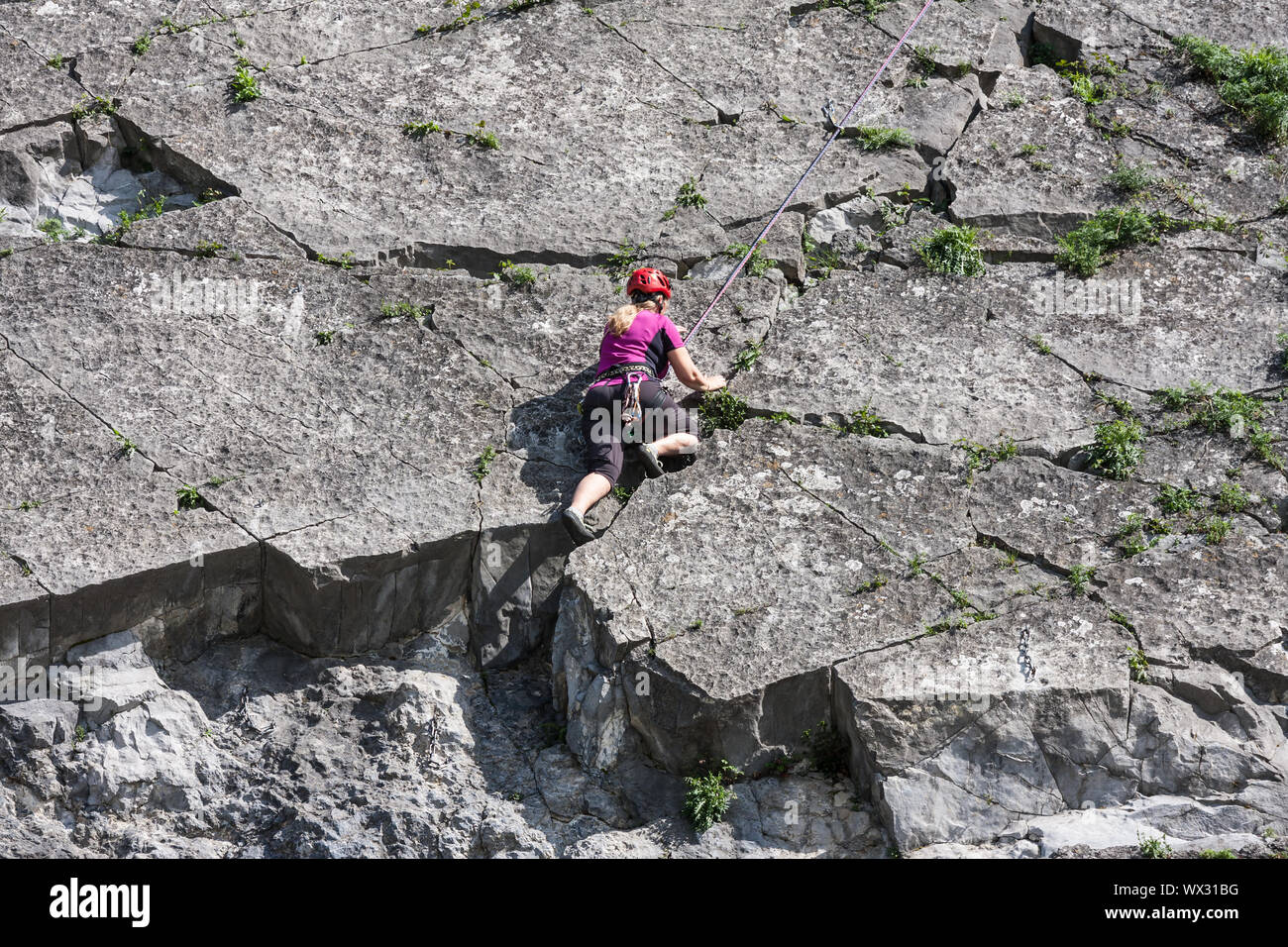 Woman climbing a vertical rock along river Meuse in Belgium Stock Photo