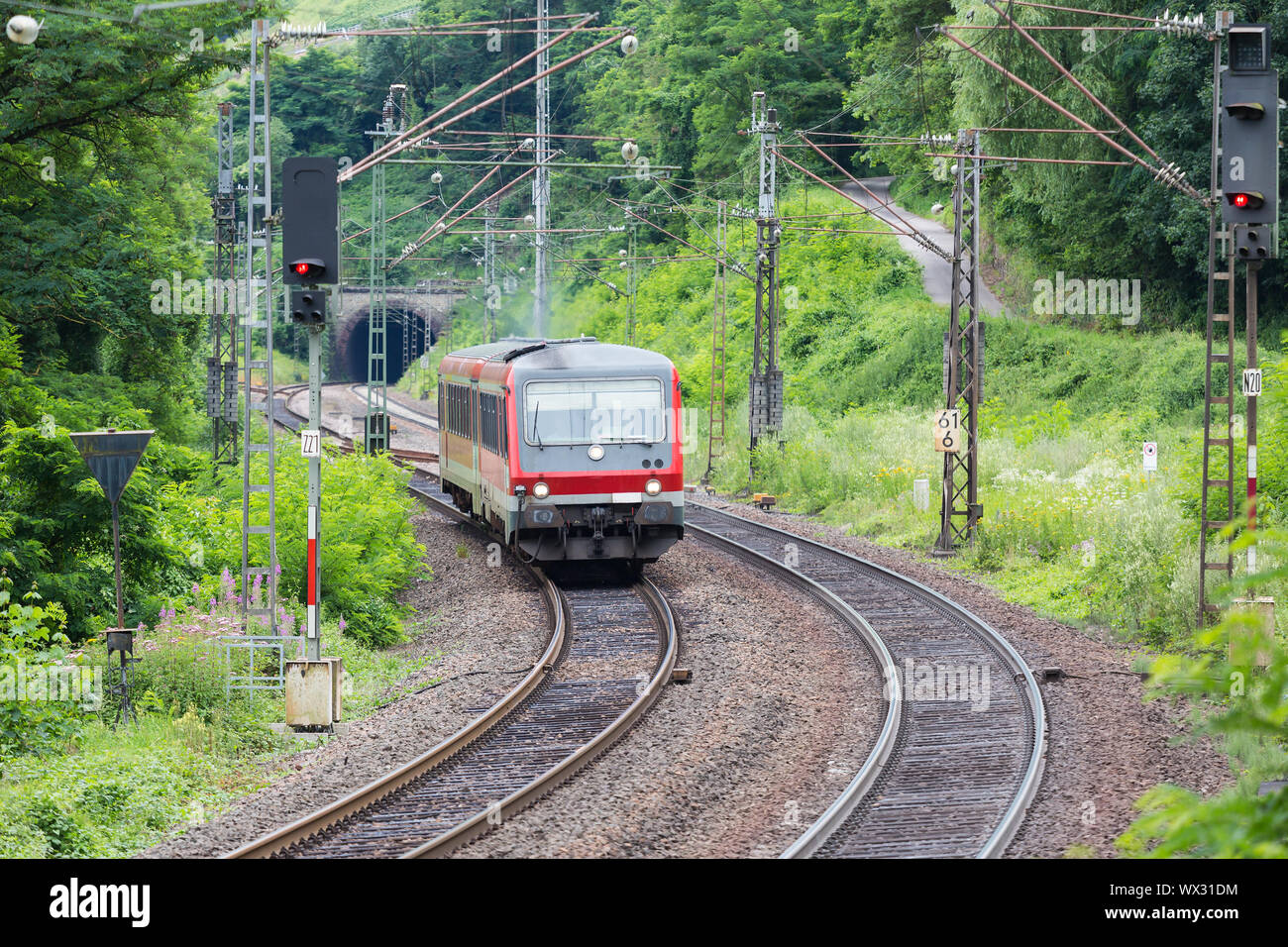 Train driving through woods near river Moselle in Germany Stock Photo