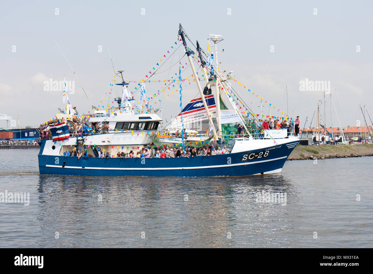 Decorated fishing ship is leaving the harbor of Urk Stock Photo