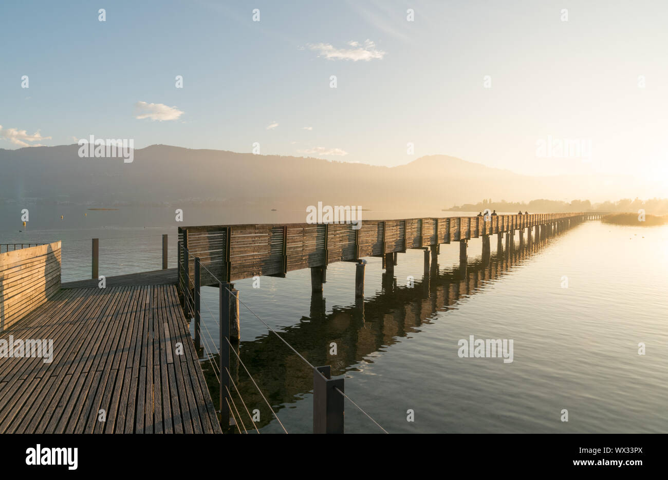 long wooden pier and boardwalk over Lake Zurich near rapperswill in golden evening light with silhou Stock Photo