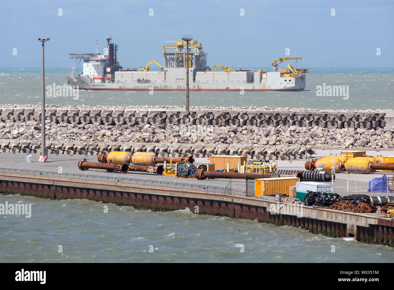 French harbor Calais with dredging ship navigating outside the harbor Stock Photo