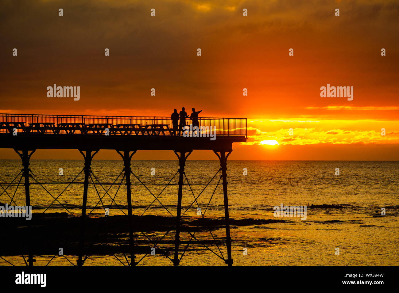 Aberystwyth, UK. 16th Sep, 2019. People standing on Aberystwyth’s Victorian seaside pier are silhouetted as they watch the last rays of the suns as it sets over Cardigan Bay, on a glorious mid autumn evening, The week ahead is expected to be warm and settled with a high pressure system dominating the weather in the southern parts of the UK Credit: keith morris/Alamy Live News Stock Photo