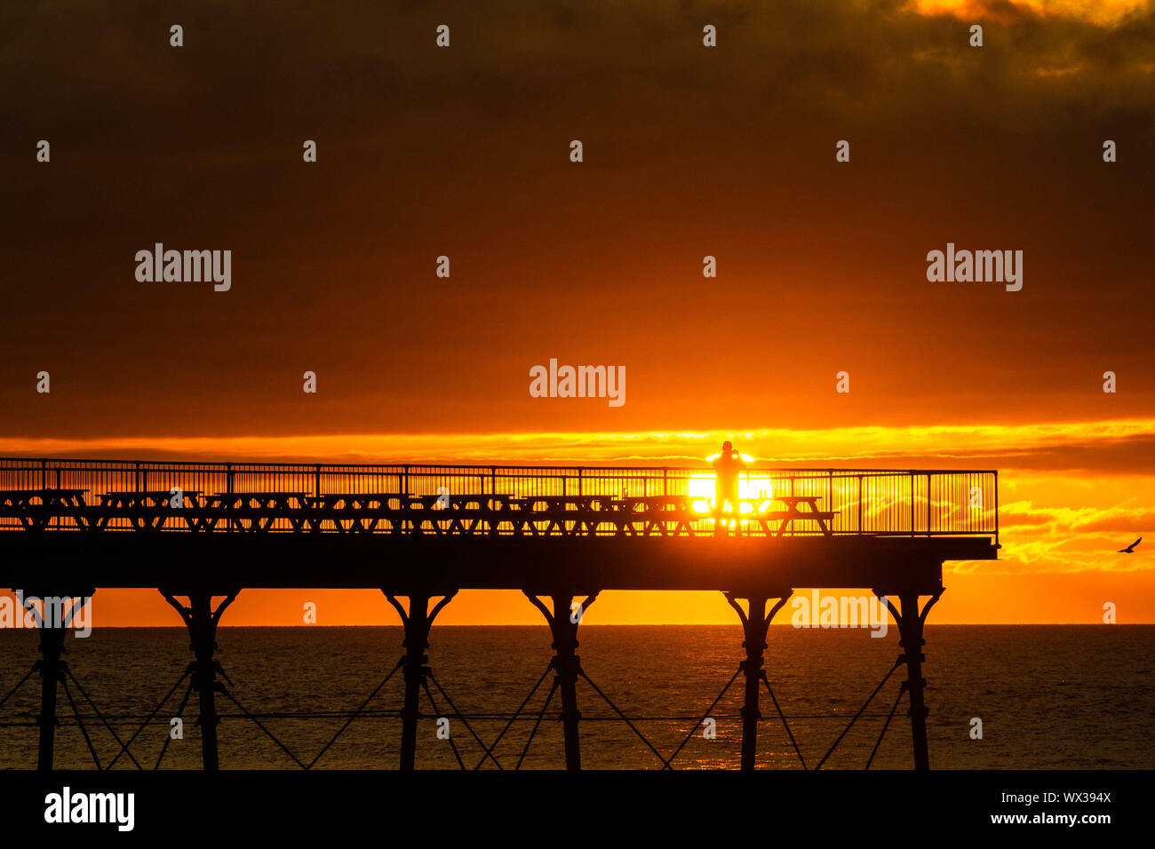 Aberystwyth, UK. 16th Sep, 2019. People standing on Aberystwyth’s Victorian seaside pier are silhouetted as they watch the last rays of the suns as it sets over Cardigan Bay, on a glorious mid autumn evening, The week ahead is expected to be warm and settled with a high pressure system dominating the weather in the southern parts of the UK. Credit: keith morris/Alamy Live News Stock Photo