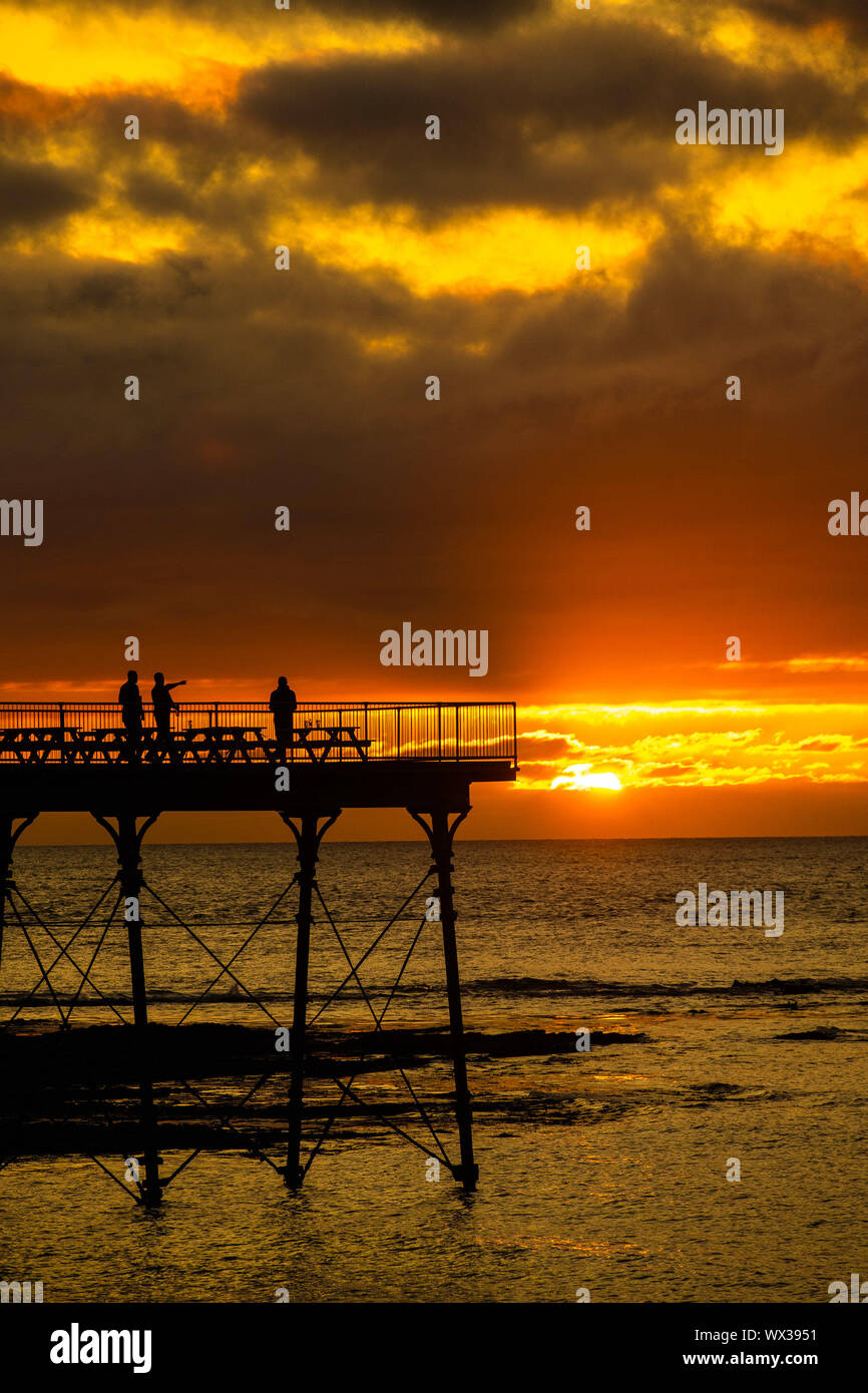 Aberystwyth, UK. 16th Sep, 2019. People standing on Aberystwyth’s Victorian seaside pier are silhouetted as they watch the last rays of the suns as it sets over Cardigan Bay, on a glorious mid autumn evening, The week ahead is expected to be warm and settled with a high pressure system dominating the weather in the southern parts of the UK Credit: keith morris/Alamy Live News Stock Photo