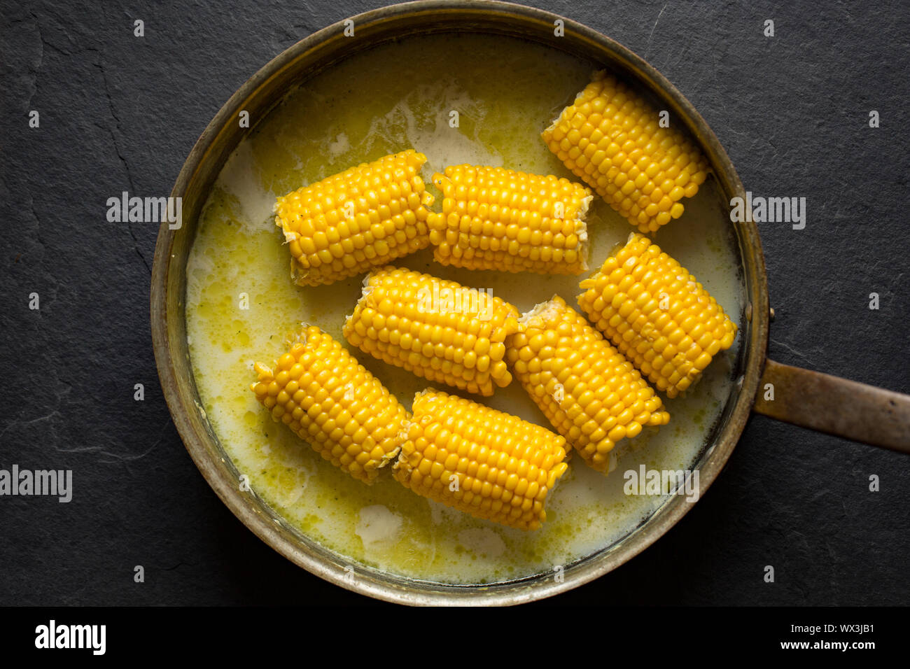 British corn on the cob that has been bought from a UK supermarket and simmered in a copper pan with milk, butter and vegetable stock. England UK GB Stock Photo