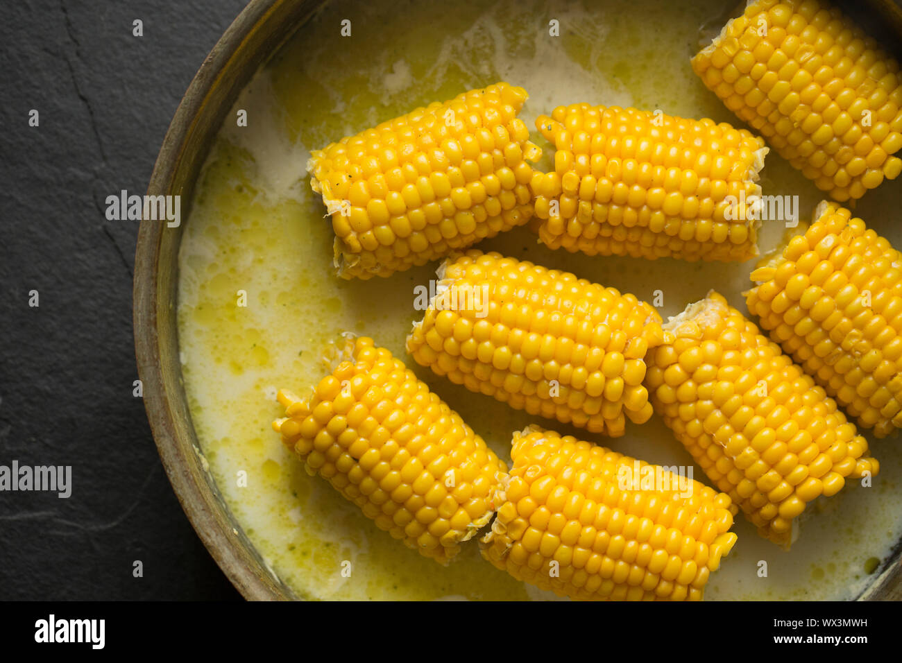 British corn on the cob that has been bought from a UK supermarket and simmered in a copper pan with milk, butter and vegetable stock. England UK GB Stock Photo