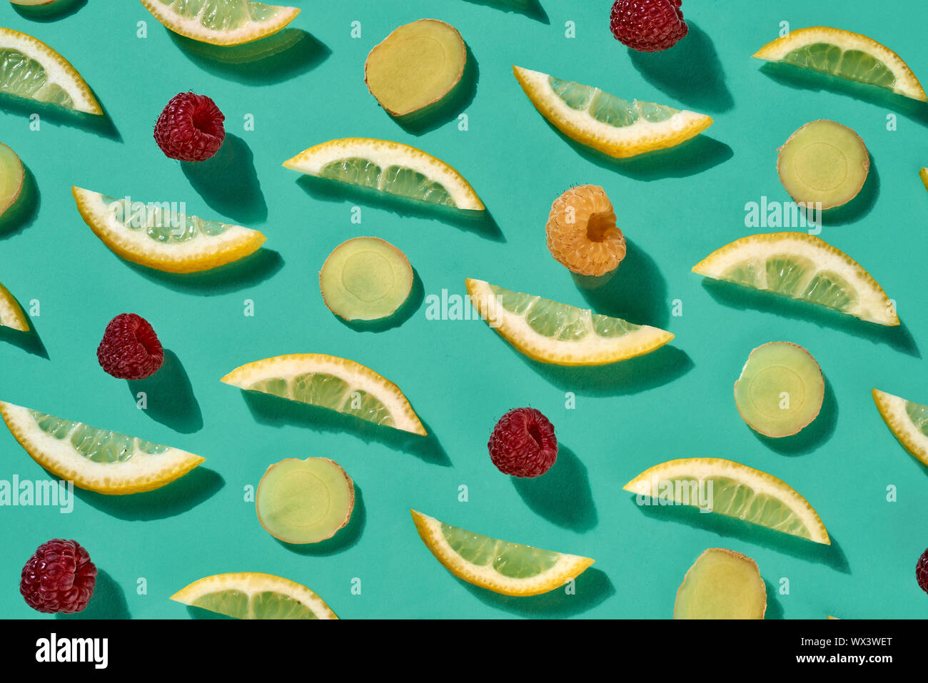 Fresh organic pattern from pieces of lemon and raspberry for healthy tea on a blue background. Food background. Flat lay Stock Photo