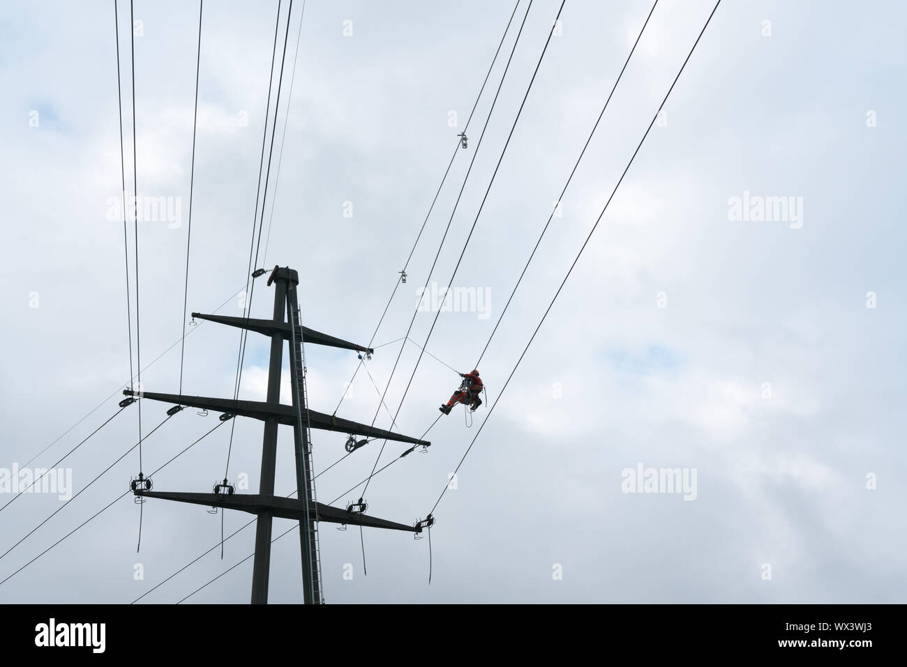 Men with safety equipment working on high voltage power lines Stock Photo
