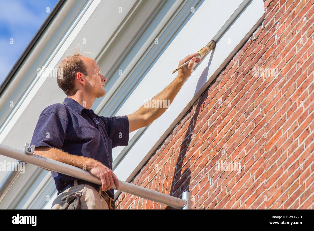 Caucasian painter painting  roof molding with brush Stock Photo