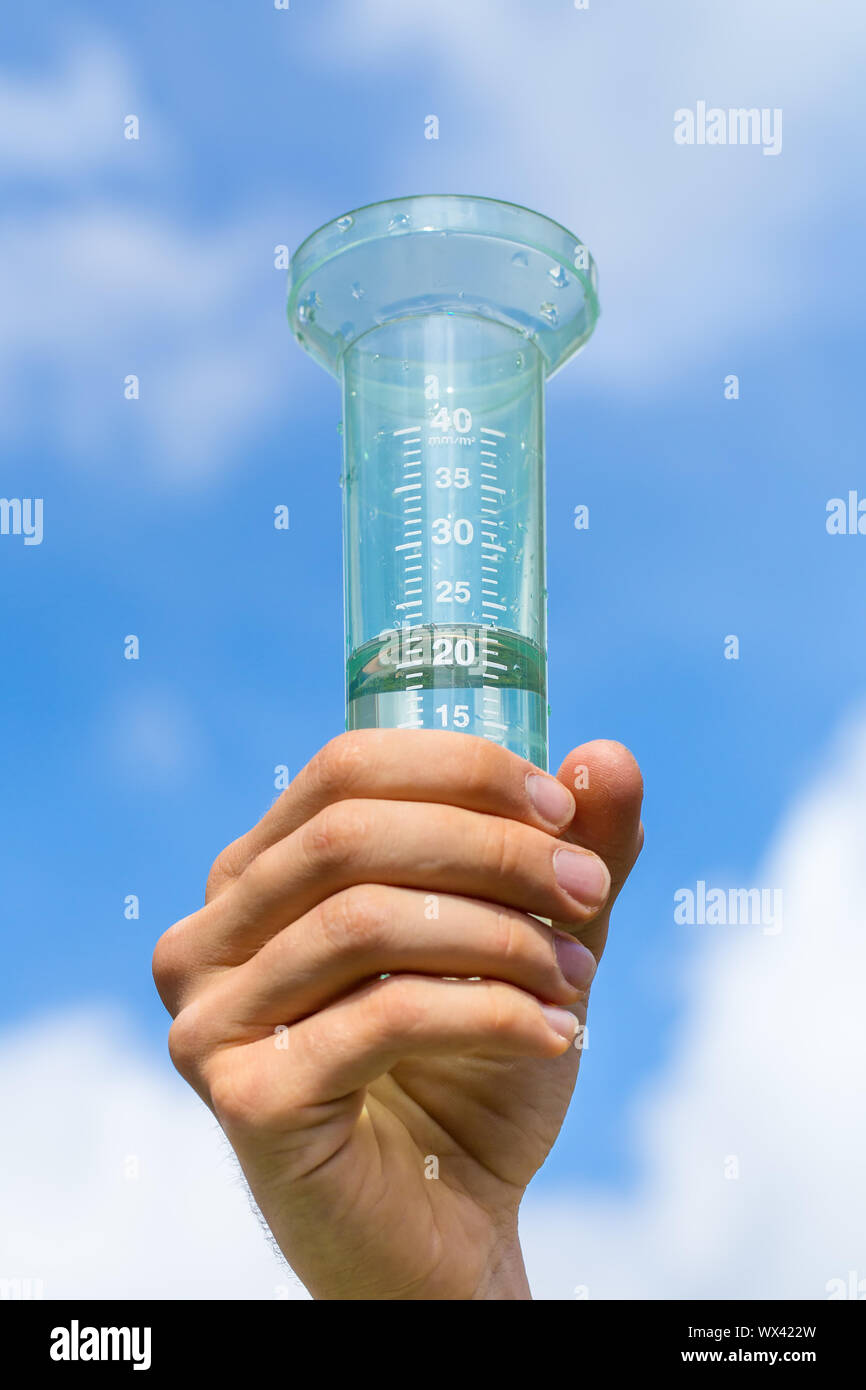 Hand holding filled water meter up in sky Stock Photo