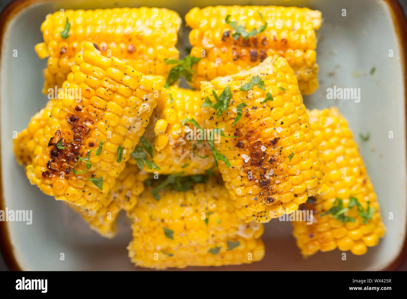 British corn on the cob that has been bought from a UK supermarket and simmered in milk, butter and vegetable stock. It has been seasoned with black p Stock Photo