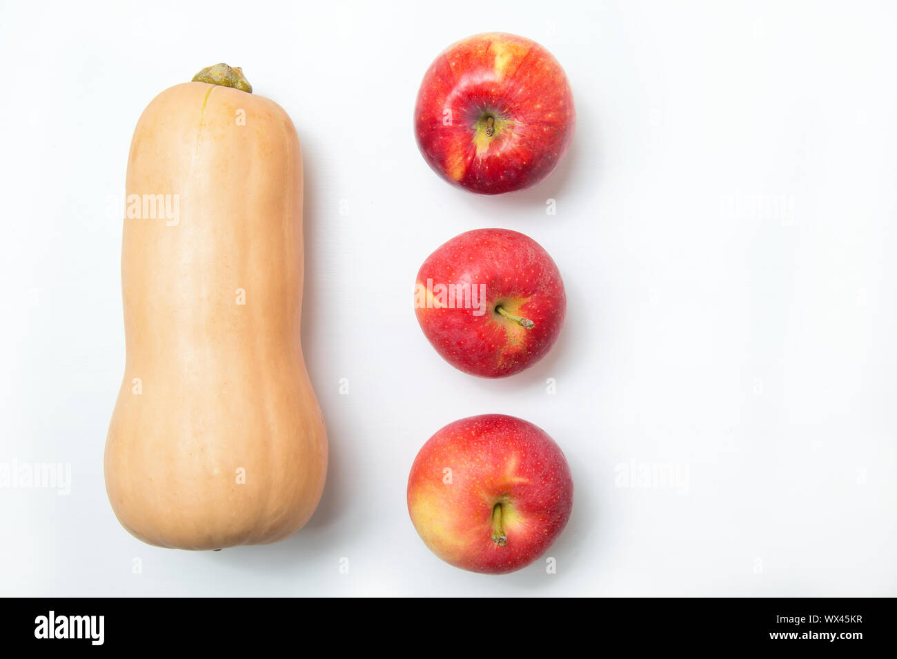 Three red apples and yellow pumpkin on a white background. Copy space. Stock Photo