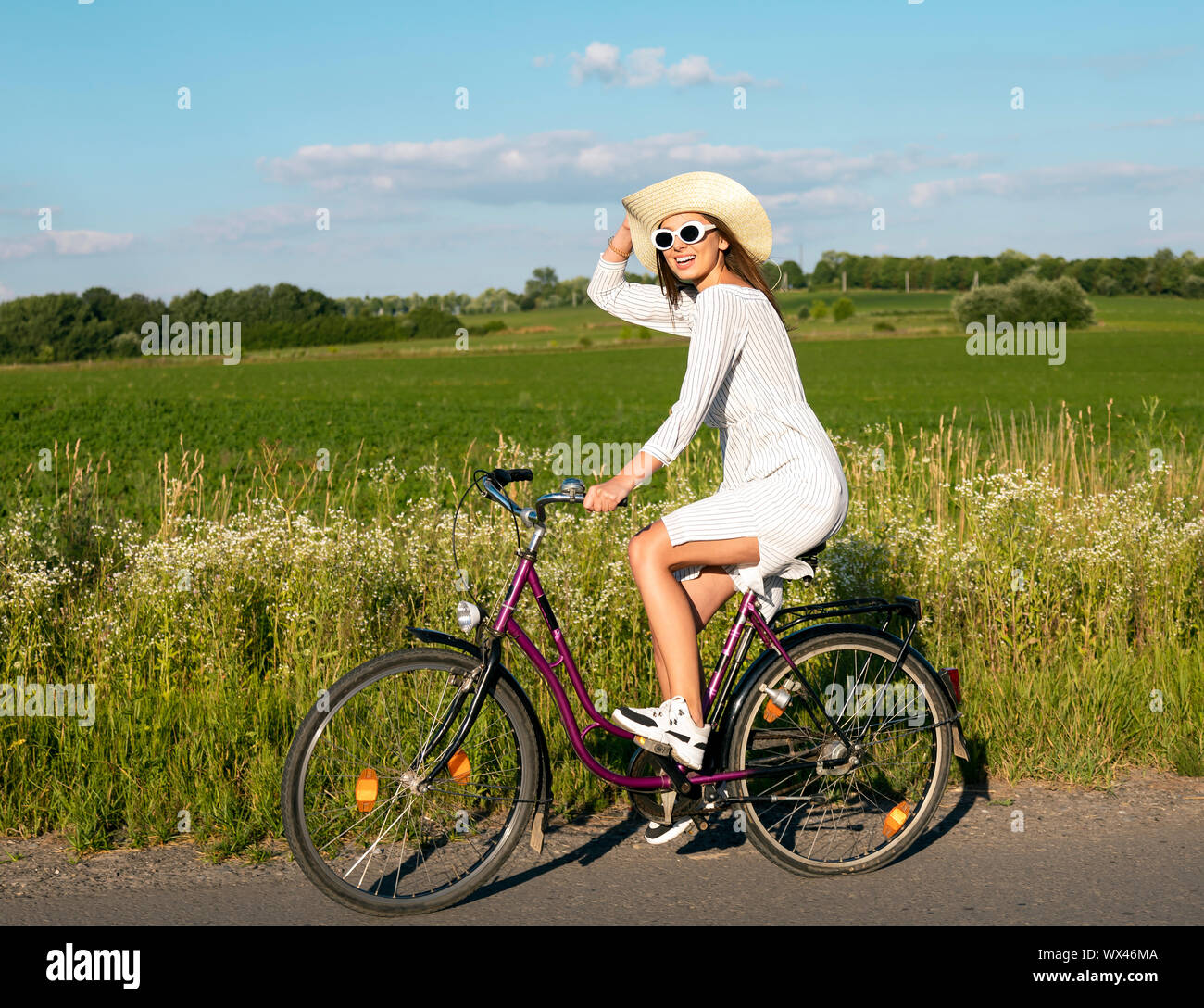 Young pretty female cyclist posing while a short break in her rural trip Stock Photo