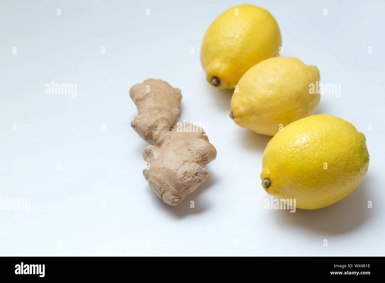 Three yellow lemons and ginger root on a light background. Stock Photo