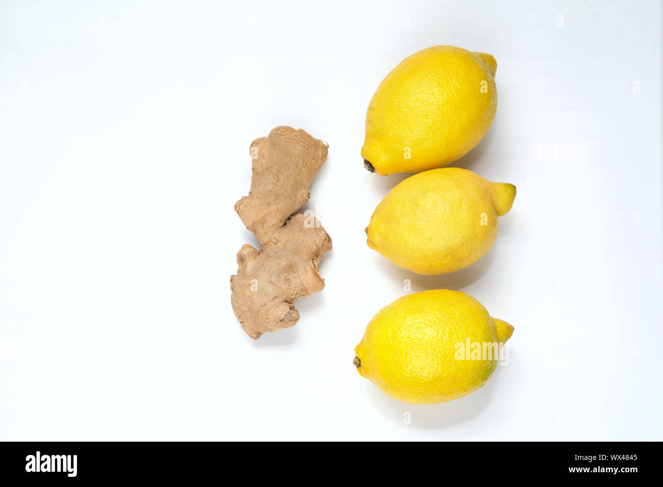 Three yellow lemons and ginger root on a light background. Stock Photo