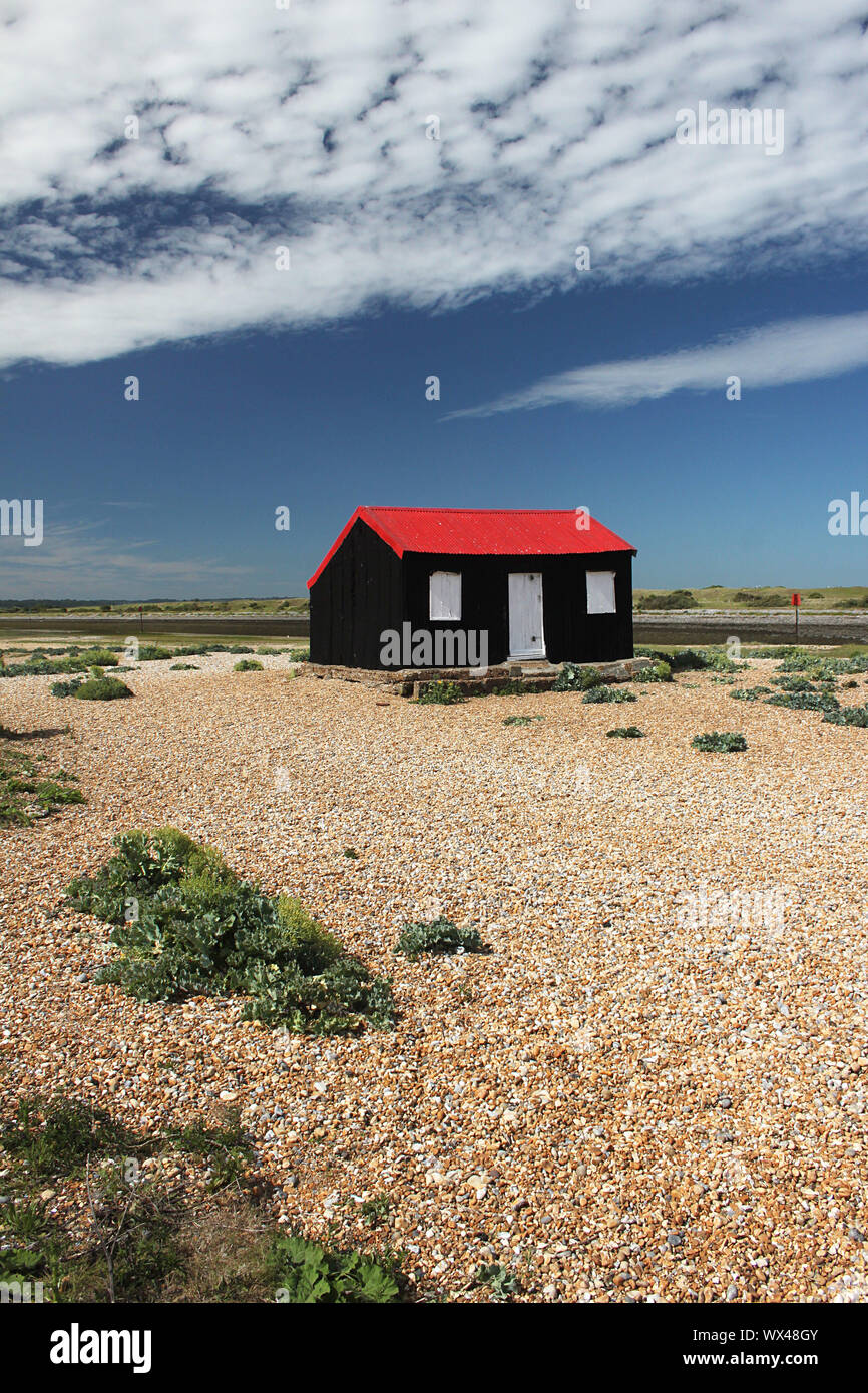 Black hut with bright red roof in Rye Harbour, East Sussex Stock Photo