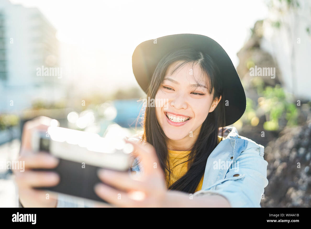 Happy Chinese influencer woman doing photo on vacation - Young trendy Asian girl taking selfie outdoor Stock Photo