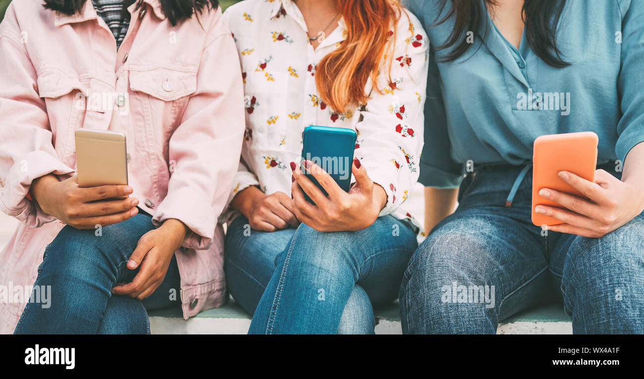 Happy Asian friends using mobile smart phone outdoor - Millennial young people addicted to new technologies trends and social media network Stock Photo