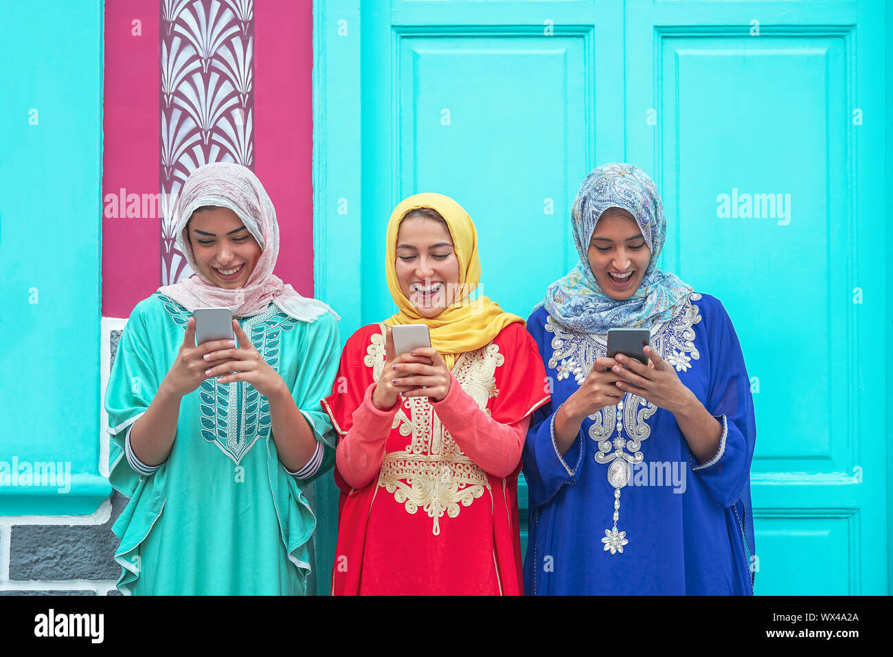 Happy muslim women using their mobile smart phones in the college - Arabian young people watching on cellphone and laughing together outdoor Stock Photo
