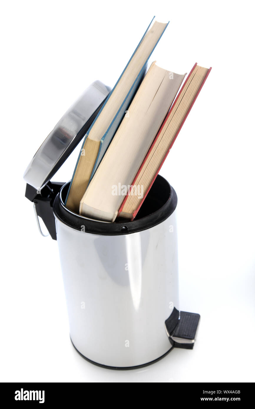 Cylindrical metal waste paper bin filled with hardcover books possibly from a student venting his or her frustration with the education system Stock Photo