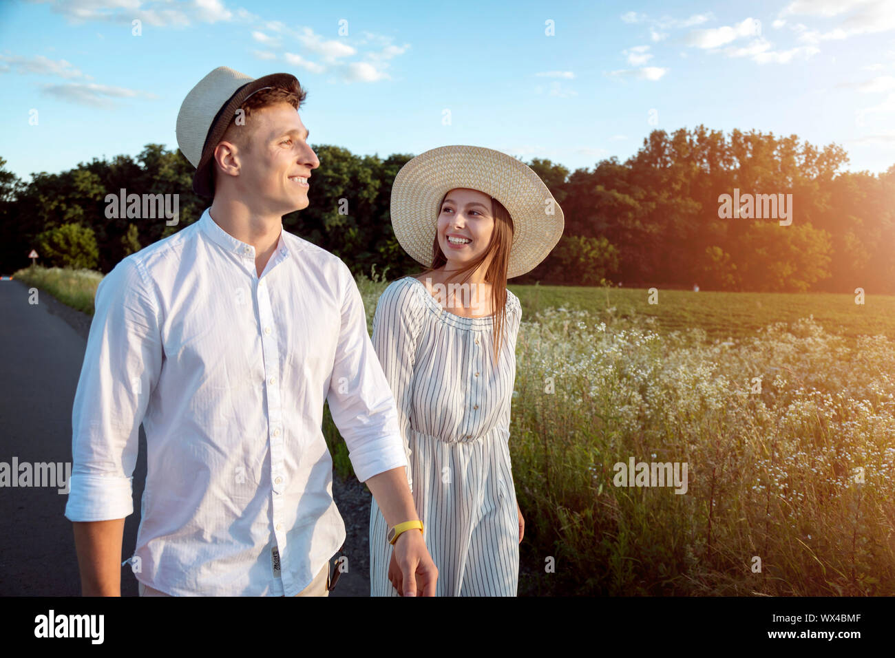 Loving couple having a walk through sunset summer countryside Stock Photo