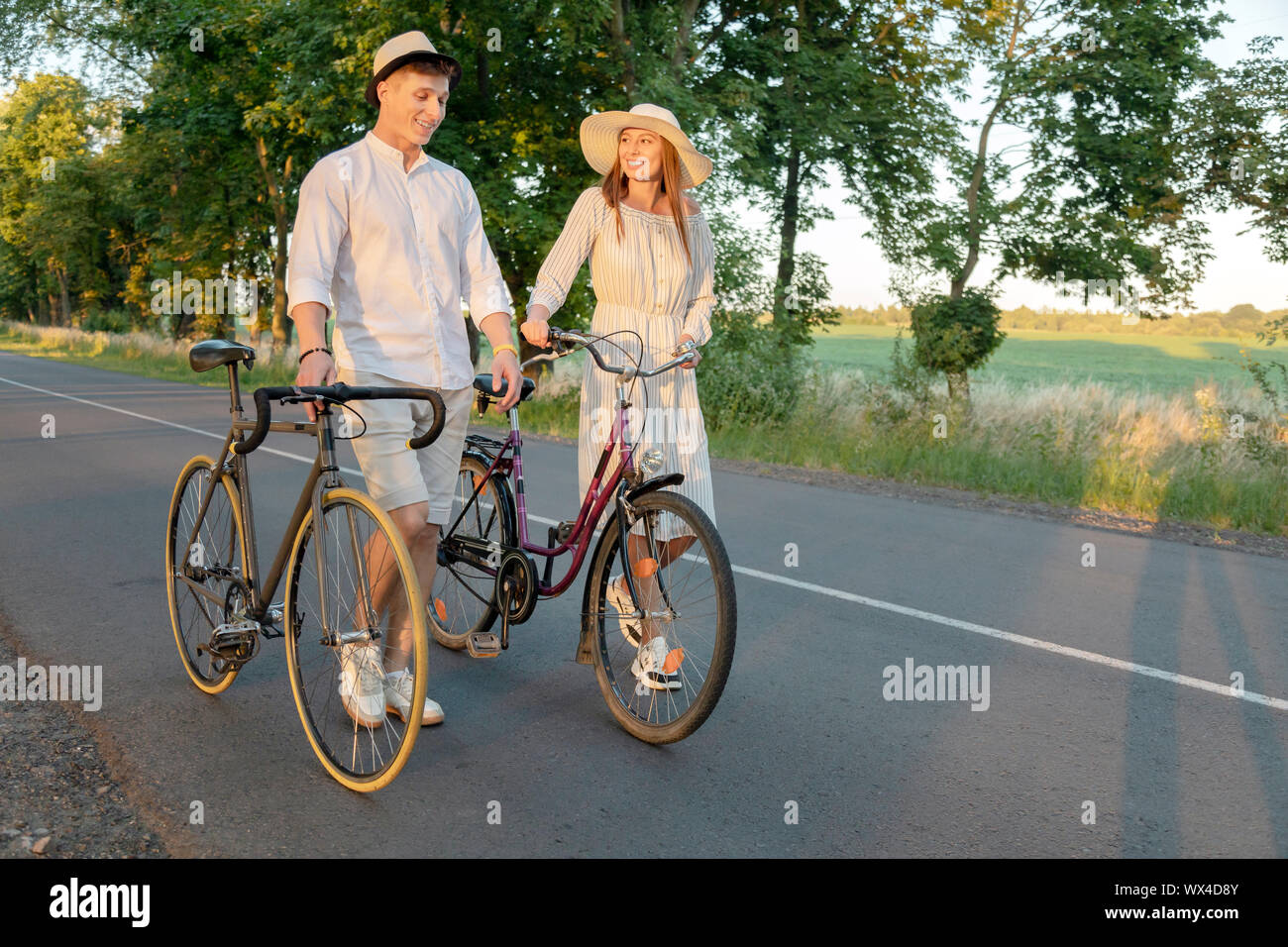 Sweet couple wheeling bikes while returning home after a wonderful summer rural trip Stock Photo