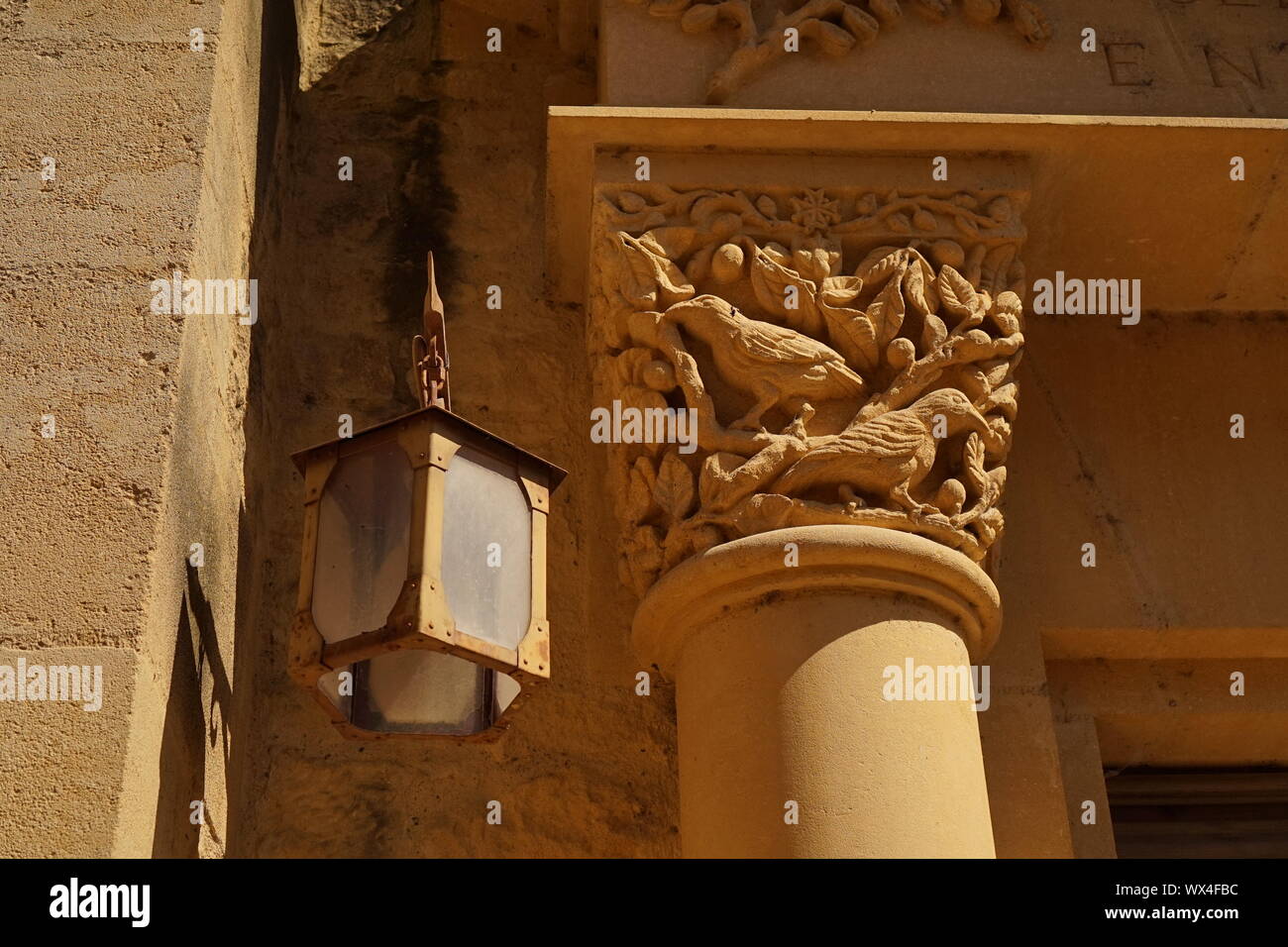 The top of an ornate stone pillar and an old lantern light hanging Stock Photo