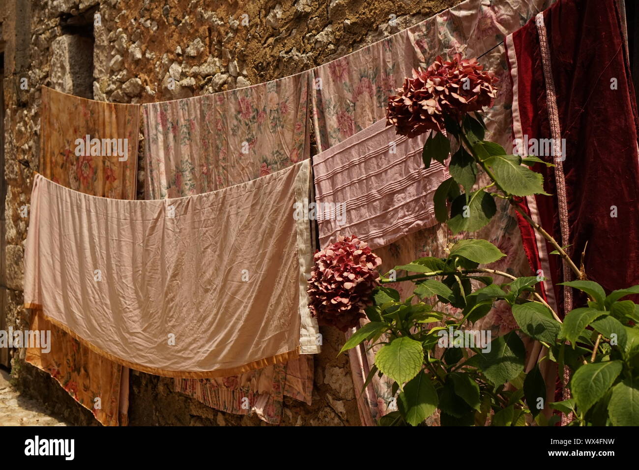 Pale pink washing hanging out to dry by a French stone wall Stock Photo