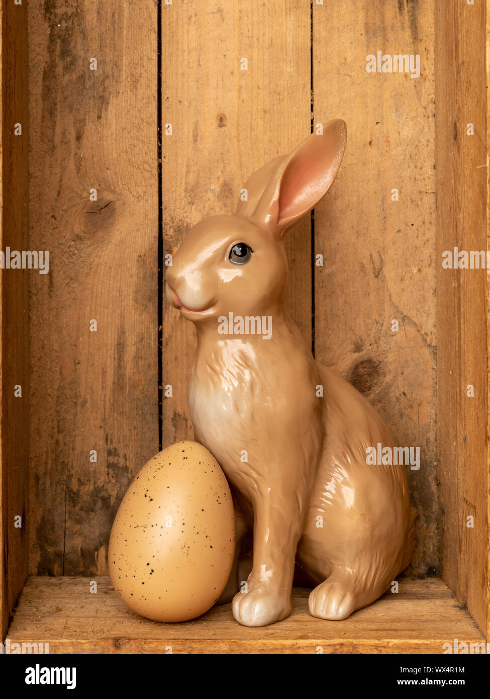 sweet easter bunny figure with an egg in a wooden box Stock Photo