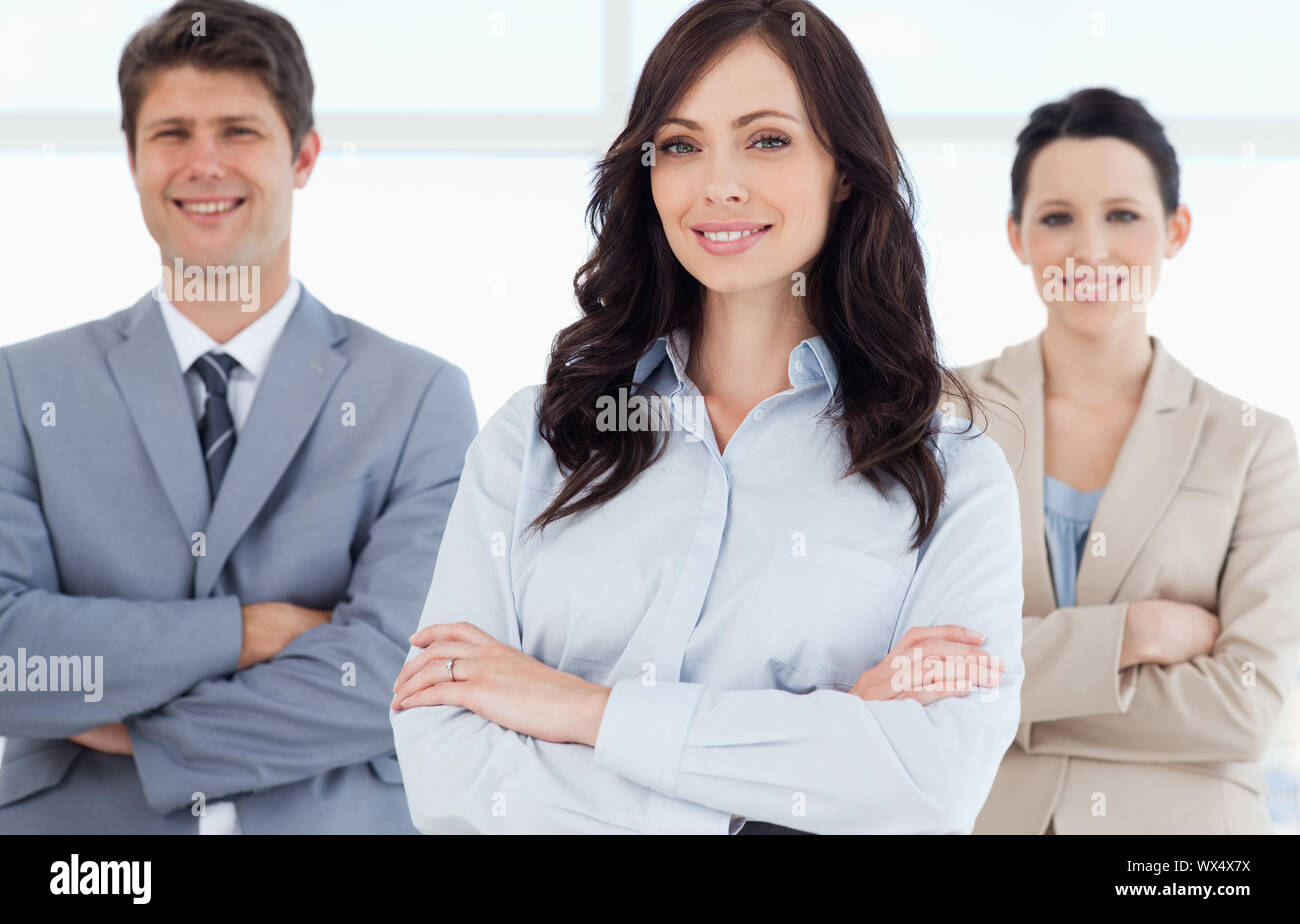 Young smiling executive woman crossing her arms in front of co-workers ...