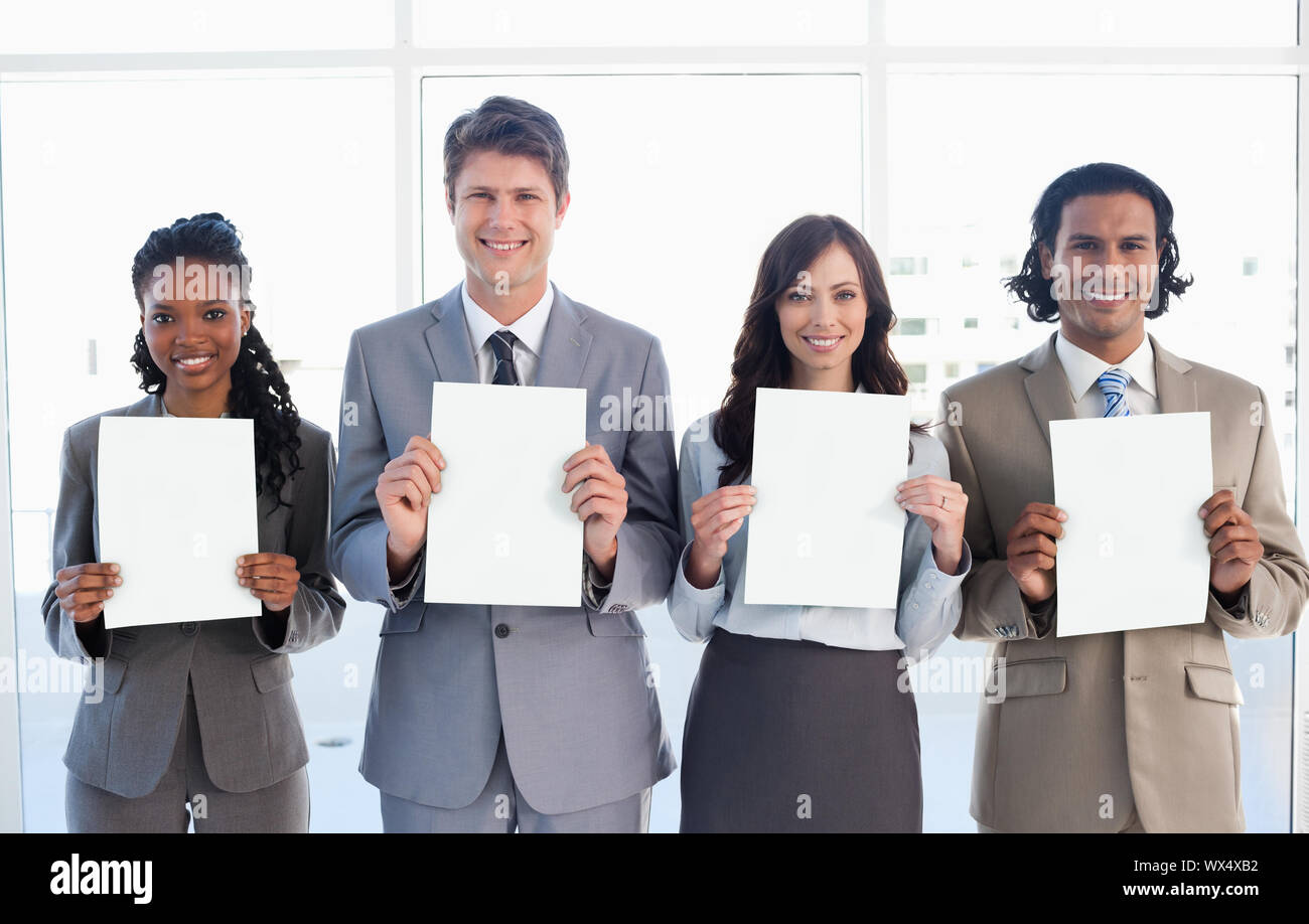 Smiling business people standing in front of a window while showing ...