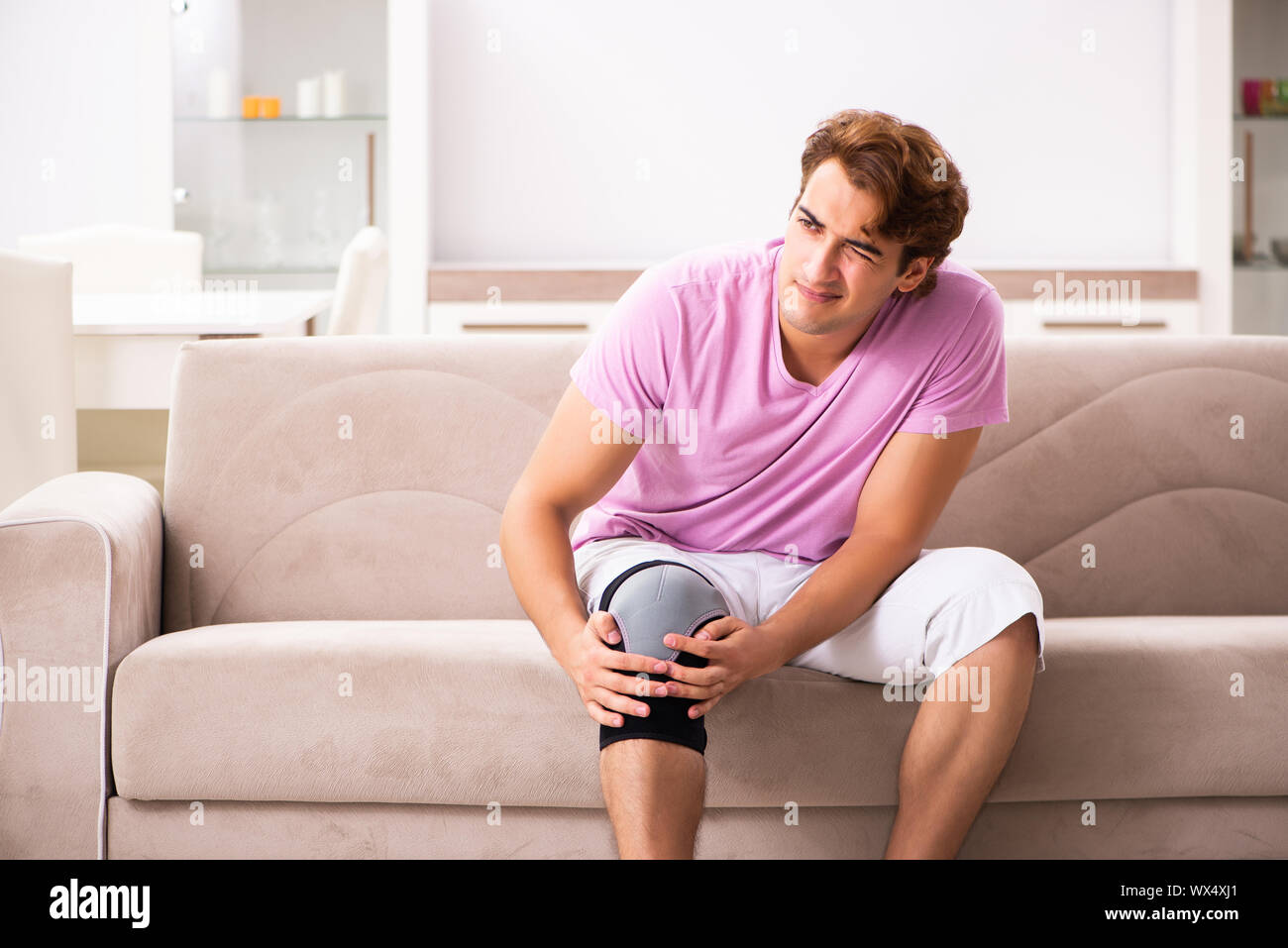 Young man with injured knee recovering at home Stock Photo Alamy
