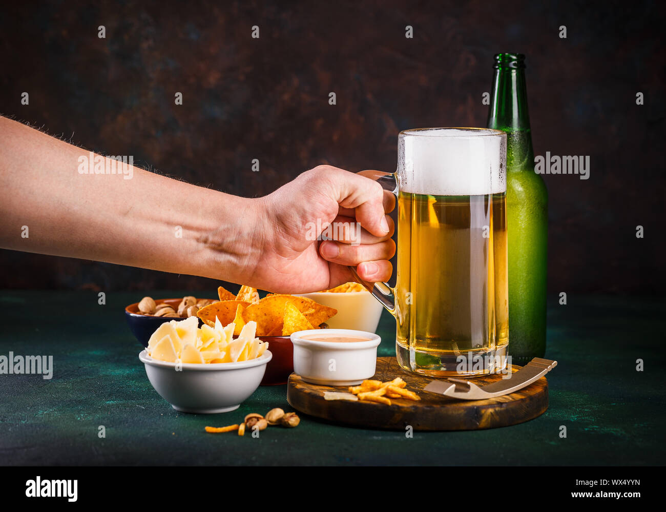 Glass mug with beer with foam and water drops and snacks on a dark green background Stock Photo